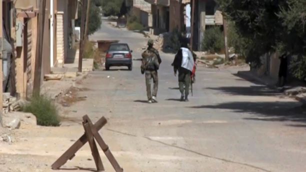 This Saturday, Oct 21, 2017 frame grab from video, shows two Syrian soldiers walking in the street of Qaryatayn, a town in central Syria which was recaptured from Islamic State group militants on Saturday. The bodies of at least 67 Syrian civilians, many summarily killed by the Islamic State group, have been discovered in Qaryatayn, activists said Monday, Oct. 23, 2017. (AP Photo)