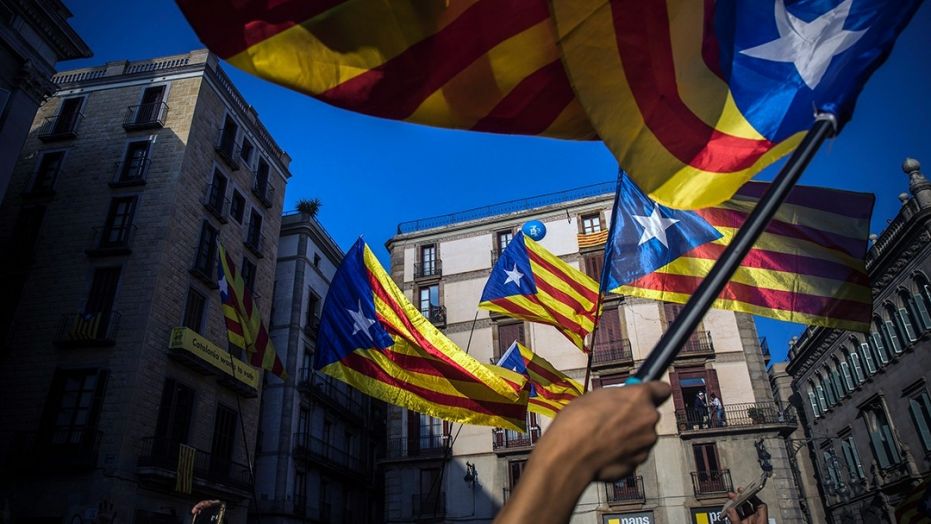 People wave Catalan flags in Barcelona Thursday after the regional president's address.