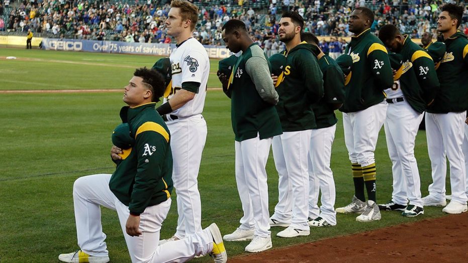 Oakland Athletics catcher Bruce Maxwell kneels during the national anthem before a game in Oakland, Calif., Sept. 23, 2017.