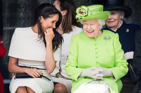 Meghan covers her mouth to contain her laughter with the Queen